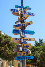 Signpost Giving Directions And Distances To Multiples Cities All Around The World On The Beach Of Cala Llonga In The Southeast Of Ibiza In The Balearic Islands, Spain