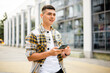 © stenkovlad - Outdoors portrait of a man who uses a phone and wireless headphones