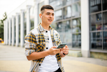 Wall Mural - Outdoors portrait of a man who uses a phone and wireless headphones