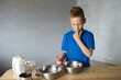 © Julia Jones - A child prepares dough in metal bowls. Trying the dough