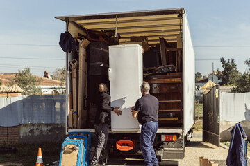 2 coworkers loading a cooler onto a moving truck