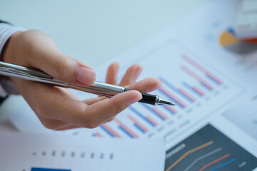 Close up of hands are working on paperworks that shows graft and chart of accounting and financial.