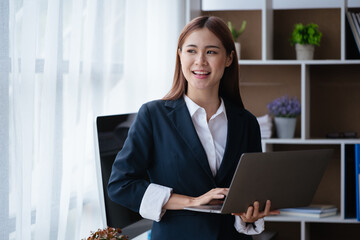 Young business women working and typing on laptop with happy and smile face on office spec.