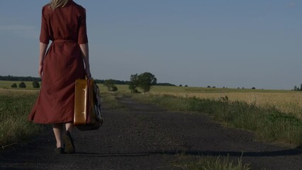 Sticker - Girl in red dress with suitcase on country road in sunset.