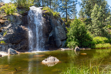 Turtles warm in the sun on rock at the Mirabeau Point Park pond and waterfall in Spokane Valley, Washington, USA.