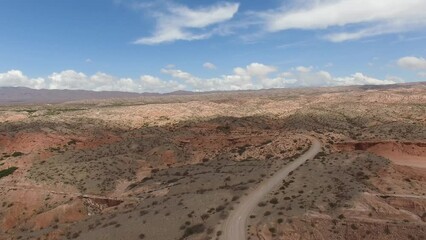 Wall Mural - Aerial view of the dirt road across the arid desert. View of the sandstone hills, dunes and canyon beautiful colors and texture. 