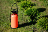 Fototapeta  - Fertilizer sprayer and a row of thujas on green lawn. Seasonal garden work concept.