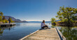 © Elena_Alex - Woman relaxes by the lake sitting on the edge of a wooden jetty. Sunny summer morning or evening concept.