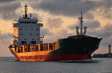 Wall Mural - Large cargo ship sailing at sunset. Baltic sea. Panoramic view from a sailboat. Freight transportation, logistics, global communications, economy, business, industry