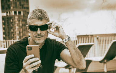 Canvas Print - Business man in casual clothes looking at business messages on a hotel rooftop.