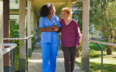 Sticker - African female doctor talking to elderly retired woman in the hospital yard. Happiness and retirement concept