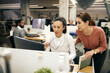© Drazen - Two businesswomen cooperating while working on desktop PC in office.