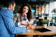 © Drazen - Businesswoman and her colleague using smart phone during meeting in cafe.