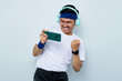 © Bangun Stock Photo - Excited young Asian sportman in blue headband and sportswear white t-shirt, playing video games on smartphone to pass difficult level wears stereo headphones on ears isolated on white background