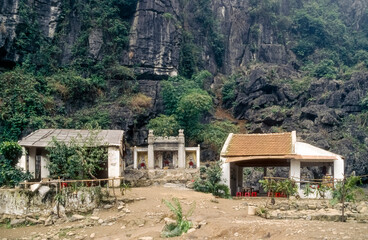 Eingescanntes Diapositiv einer historischen Farbaufnahme einer buddhistischen Tempelanlage am Fusse eines Felsens in Nordvietnam