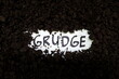 Bury grudge and stop holding concept. Grudge text word on soil backdrop.