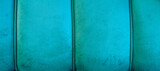 Fototapeta  - Turkusowe aksamitne tło. Zdjęcie panoramiczne turkusowego obicia, widoczne przeszycia, miękki i puchaty materiał, miejsce na tekst.