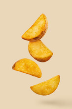 Delicious Fried Potato Wedges, Flying In The Air, Isolated On Pastel Peach Background