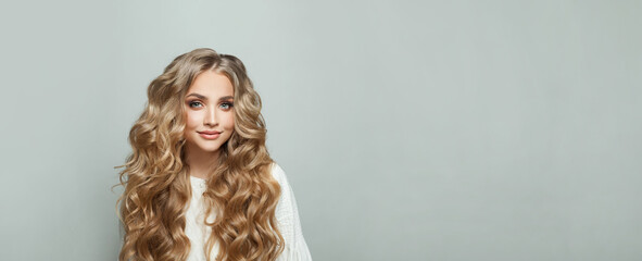 Wall Mural - cheerful attractive blonde young woman with long healthy silky wavy hair smiling against white studi