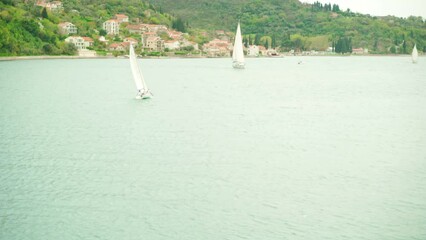 Wall Mural - A sailboat floats on the sea against the backdrop of mountains on a summer day