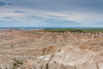 Wall Mural - Colorful hills on the background of green field, under a blue sky in Badlands National Park, USA