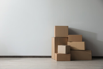 Wall Mural - Many closed cardboard boxes on floor near white wall, space for text. Delivery service