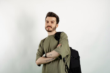 Wall Mural - Portrait of cheerful man wearing khaki t-shirt posing isolated over white background confident posing carrying backpack with crossed arms.