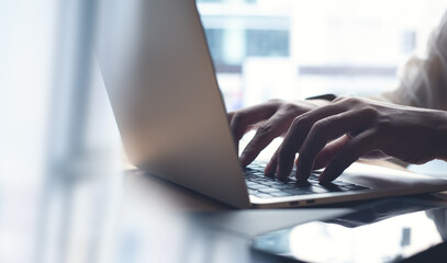 Business man working on laptop computer, typing on laptop keyboard on office table, surfing the internet, online job, online study, e-learning, working at home, telecommuting concept