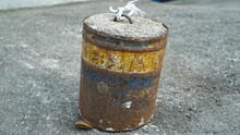 A Rusty Barrel Full Of Cement On Asphalt