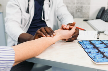 A close-up of an African-American doctor checks the heartbeat and pulse on the patient's wrist