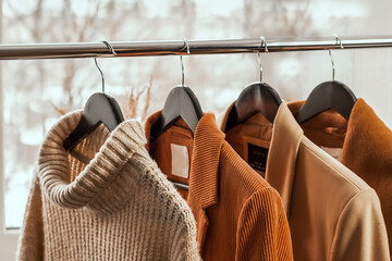 various knitted clothes, cashmere sweaters on hangers.capsule clothing in beige tones close-up. clas