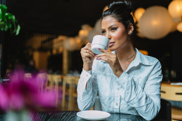 Latin woman in a cafe drinking coffee.