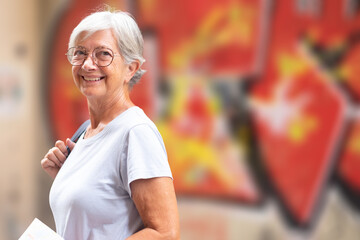 Attractive smiling senior woman on vacation in Seville, Spain, walking around the old city looking at camera