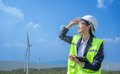 Wall Mural - Asian woman Power engineer are working with wind turbines.Electrical engineer female Renewable Energy power plant Sustainability concept.Professional Expert wind power clean energy farm.