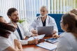 © Kostiantyn - Group of doctors sitting at meeting table in conference room during medical seminar