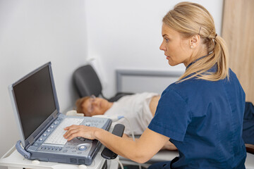 Wall Mural - Focused doctor ultrasound examine senior patient abdomen at hospital. Prenatal diagnosis center