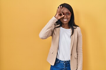 Canvas Print - African young woman wearing glasses doing ok gesture with hand smiling, eye looking through fingers with happy face.