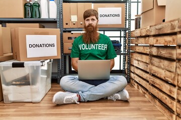 Poster - Caucasian man with long beard wearing volunteer t shirt using laptop thinking attitude and sober expression looking self confident