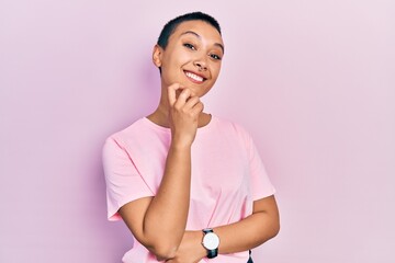 Poster - Beautiful hispanic woman with short hair wearing casual pink t shirt looking confident at the camera smiling with crossed arms and hand raised on chin. thinking positive.