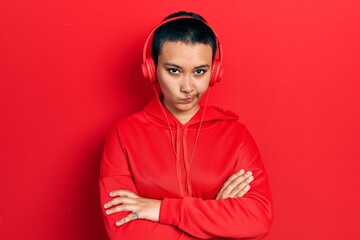 Sticker - Beautiful hispanic woman with short hair listening to music using headphones skeptic and nervous, disapproving expression on face with crossed arms. negative person.