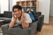 © Krakenimages.com - Young hispanic man listening to music lying on the sofa at home.