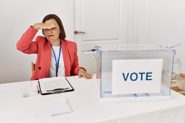 Poster - Beautiful middle age hispanic woman at political election sitting by ballot covering eyes with hand, looking serious and sad. sightless, hiding and rejection concept