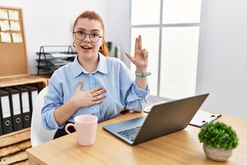 Sticker - Young redhead woman working at the office using computer laptop smiling swearing with hand on chest and fingers up, making a loyalty promise oath