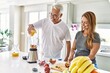 © Krakenimages.com - Middle age hispanic couple pouring juice on mixer machine cooking smoothie at the kitchen.