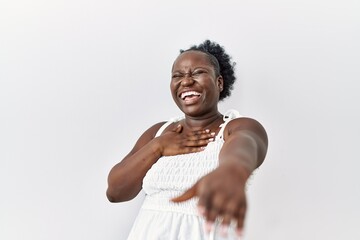 Sticker - Young african woman standing over white isolated background laughing at you, pointing finger to the camera with hand over body, shame expression