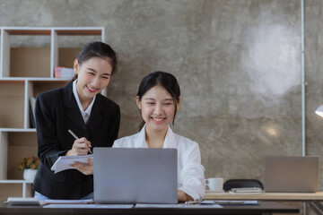 Wall Mural - Atmosphere in the office of a startup company, two female employees are discussing, brainstorming ideas to working on summaries and marketing plans to increase sales and prepare reports to managers.