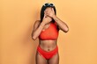 © Krakenimages.com - Young african american girl wearing bikini covering eyes and mouth with hands, surprised and shocked. hiding emotion