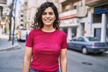 Wall Mural - Young latin woman smiling confident standing at street