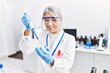© Krakenimages.com - Middle age grey-haired woman wearing scientist uniform using pipette at laboratory