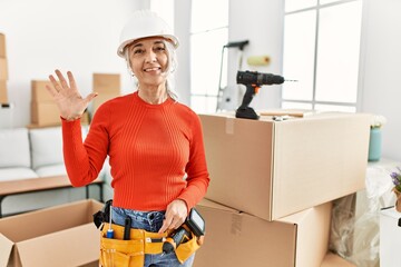 Poster - Middle age grey-haired woman wearing hardhat standing at new home showing and pointing up with fingers number five while smiling confident and happy.